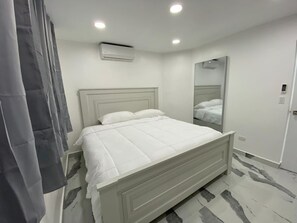 Een moderne slaapkamer met een bed, een spiegel en een airconditioning.
