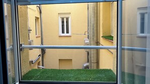 A window with a view of a building's exterior, including a window, a small balcony with artificial grass, and a metal railing. - Ler & Le Pety Palace Madrid gran vía  (Madrid)