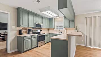 Une cuisine avec des meubles de couleur turquoise, un îlot central, un four à micro-ondes et un four encastré.
