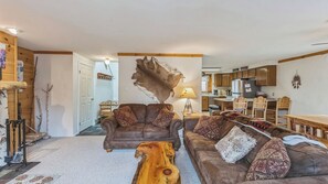 A cozy living room with a brown leather sofa, a wooden coffee table, and a large wall-mounted animal hide. - Lower Darby by Avantstay Indoor Heated Pool + Billiards + Foosball Near Gore (North Creek)
