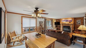 A cozy living room with a wooden dining table, a sofa, rocking chairs, a fireplace, and a television. - Lower Darby by Avantstay Indoor Heated Pool + Billiards + Foosball Near Gore (North Creek)