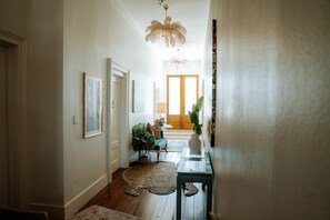 A hallway with wooden flooring, a rug, a table, and a door leading to another room. - Sugars INN Room #2 in Galveston (Galveston)