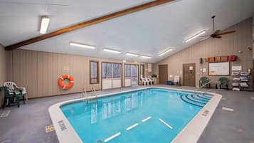 An indoor swimming pool with clear lane markings, a lifebuoy, and a ceiling fan.