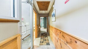 A narrow hallway with wooden paneling, a patterned rug, a 'NO SMOKING' sign, and a door leading to another room.