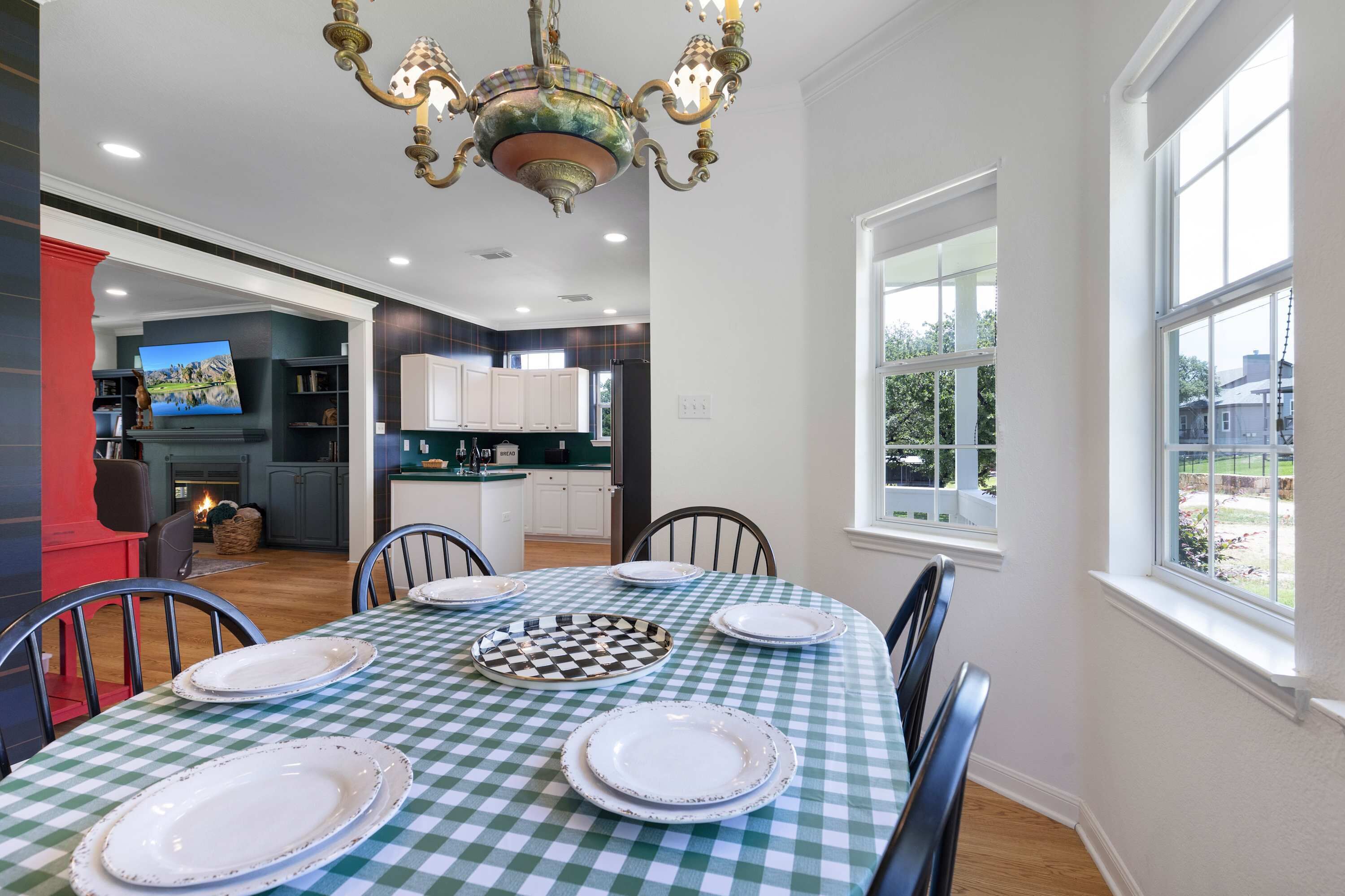 A dining area with a checkered tablecloth, white plates, and a chandelier.