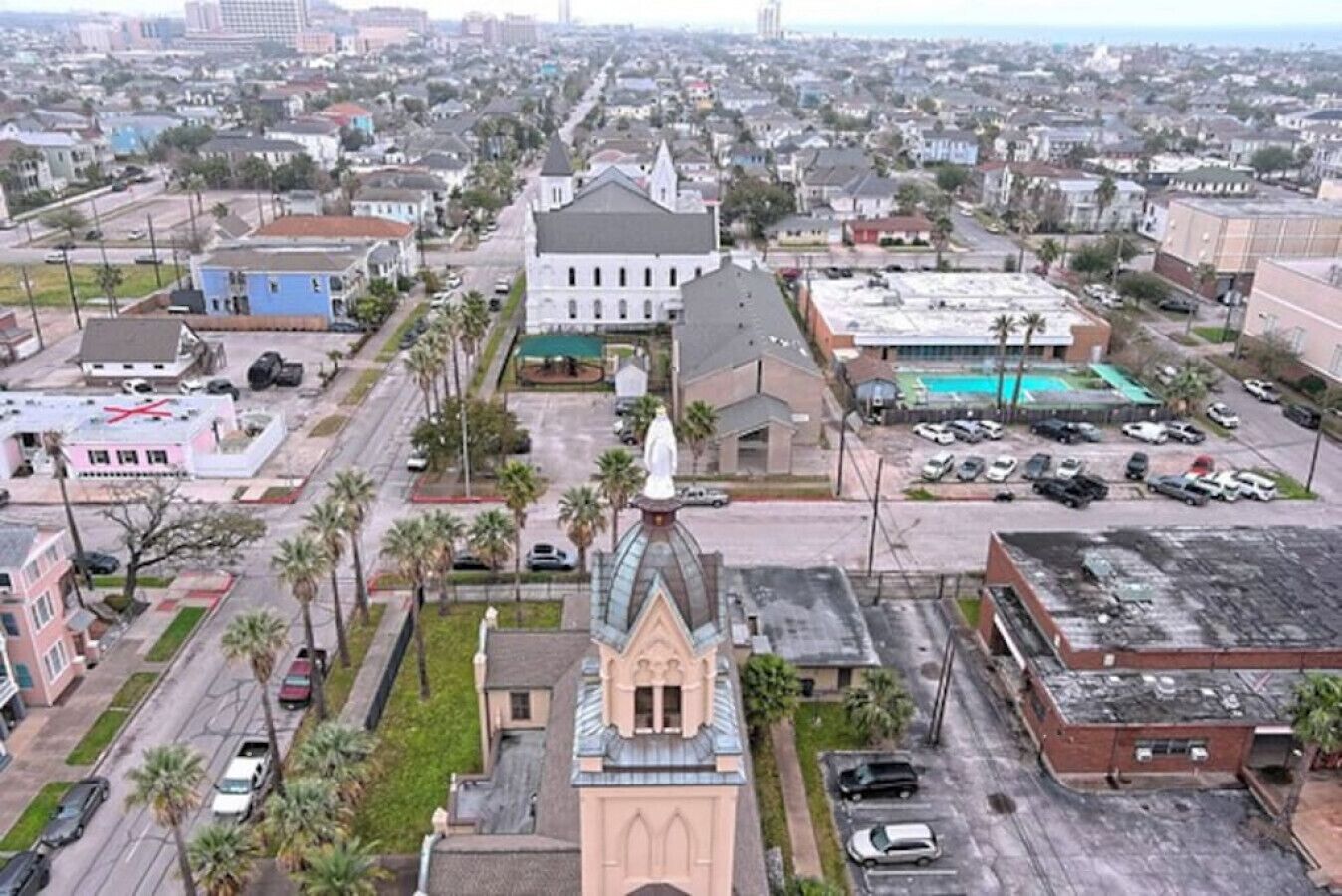 Vue aérienne d’une ville avec une église imposante, un parking et des immeubles d’habitation.