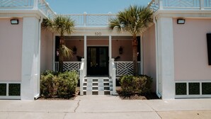 A building with a number '520' above the entrance, a white and beige color scheme, and a checkered staircase leading to the door. - Room #10 The Oleander Hotel Galveston (Galveston)