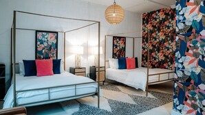 A room with two four-poster beds, a hanging light fixture, and a floral-patterned wall. - Room #10 The Oleander Hotel Galveston (Galveston)