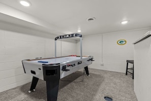 A room with a foosball table, a small stool, and a wall-mounted logo.