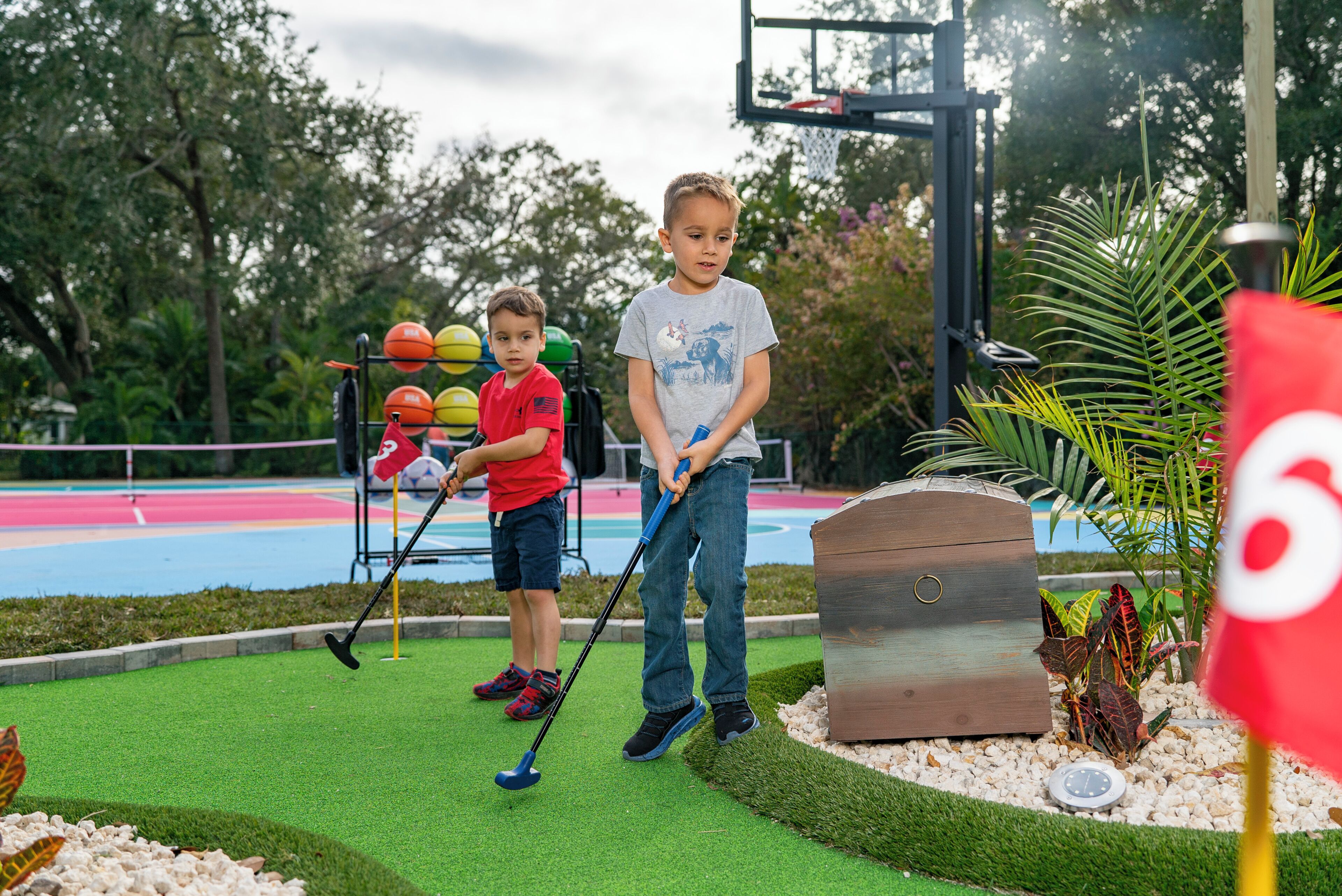 Un campo de mini golf con césped artificial verde, un obstáculo de madera y un fondo colorido.