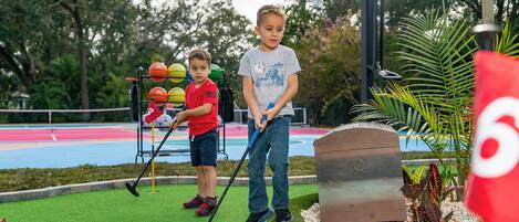 Un campo de mini golf con césped artificial verde, un obstáculo de madera y un fondo colorido.