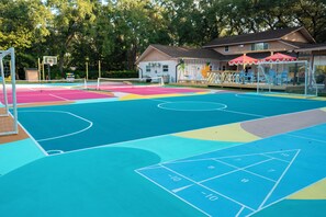 A colorful playground with a basketball court, a soccer goal, and a seating area with umbrellas. - 7BR Private Resort with EPIC SPORT COURT• Pool Cinema • Karaoke (Clearwater)