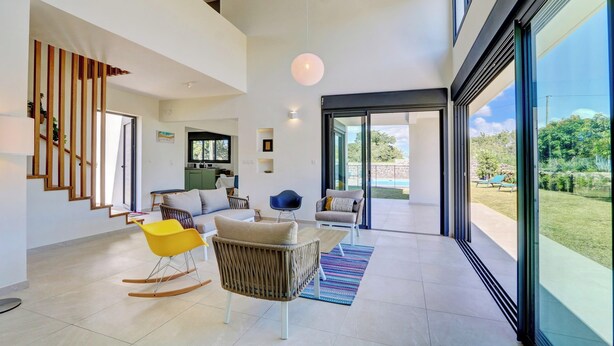 Un interno moderno con una scala, un'area salotto e ampie finestre.