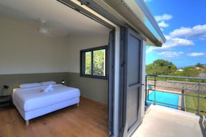 Ein Schlafzimmer mit Bett, Fenster und Blick auf einen Pool.