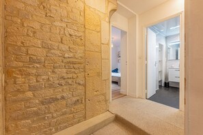 Ein Korridor mit einer Steinwand, einem Teppichboden und einer Tür zu einem Badezimmer.