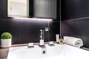 A modern bathroom with a large sink, a mirror, a potted plant, and toiletries. - Aldgate East Apartment With Balcony (London)