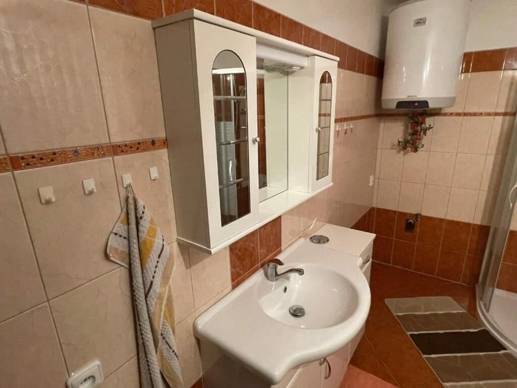 Een badkamer met een wastafel, spiegel en douche.