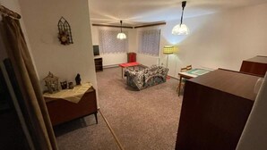 Quarto com cama, uma mesinha, luminária e janela.