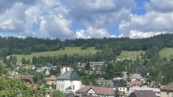 Eine Stadt mit einer Kirche, Wohnhäusern und einem bewaldeten Hügel im Hintergrund.