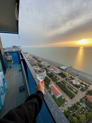 A balcony with a view of the sea and buildings at sunset. -  Apart- Hotel Orbi City u MariNika  (Batumi)