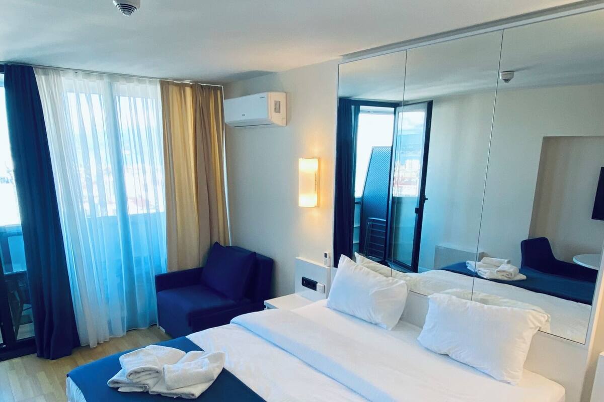 Habitación de hotel con una cama grande, una silla, un escritorio y un espejo.