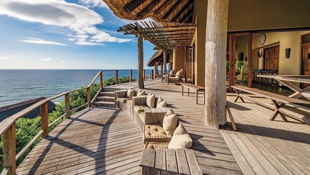 Una terraza de madera con asientos y vista al océano.