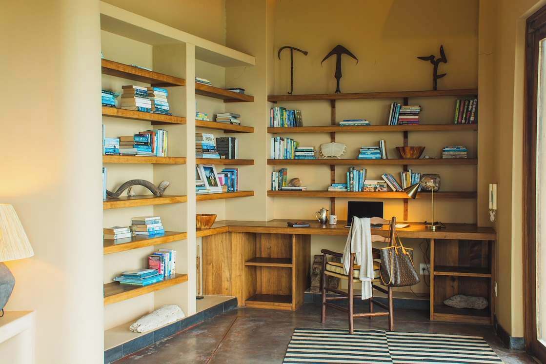 Un coin lecture chaleureux avec des étagères en bois, un bureau et un fauteuil confortable.