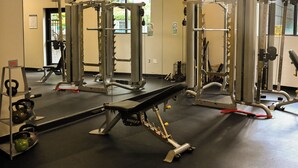 Ein Fitnessraum mit Gewichthebersportgeräten, einer Bank und Kettlebells.