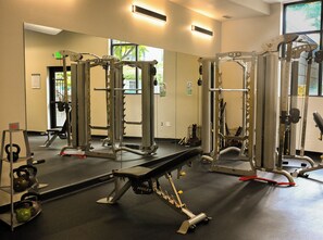 Ein Fitnessraum mit Gewichthebersportgeräten, einer Bank und Kettlebells.