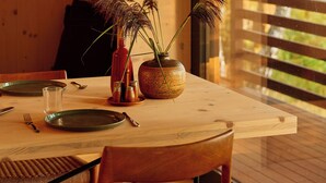 A dining table set with plates, cutlery, and a vase with plants. - Architect-designed cabin with Harefjord views (Säffle)