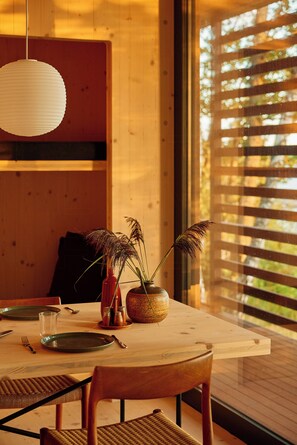 A dining table set with plates, cutlery, and a vase with plants. - Architect-designed cabin with Harefjord views (Säffle)