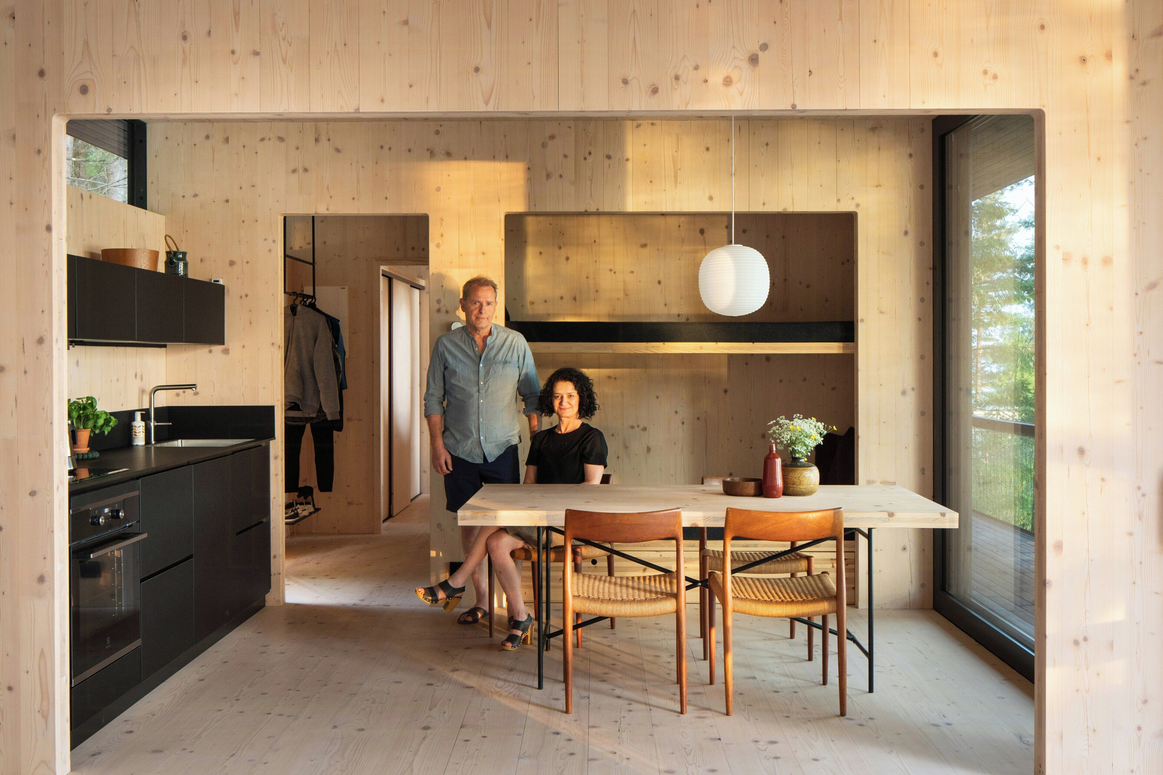 Une cuisine moderne avec des murs en bois, un coin repas avec une table et des chaises, et une grande fenêtre.