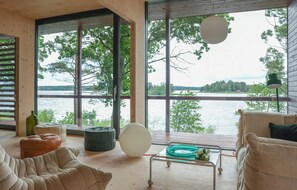A modern interior with large windows, a wooden floor, and a view of a lake. - Architect-designed cabin with Harefjord views (Säffle)