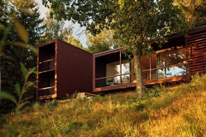 A modern cabin with a glass facade, wooden exterior, and a natural setting. - Architect-designed cabin with Harefjord views (Säffle)