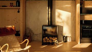 En mysig stuga med en vedeldad kamin, en soffa, en fåtölj och en matplats.