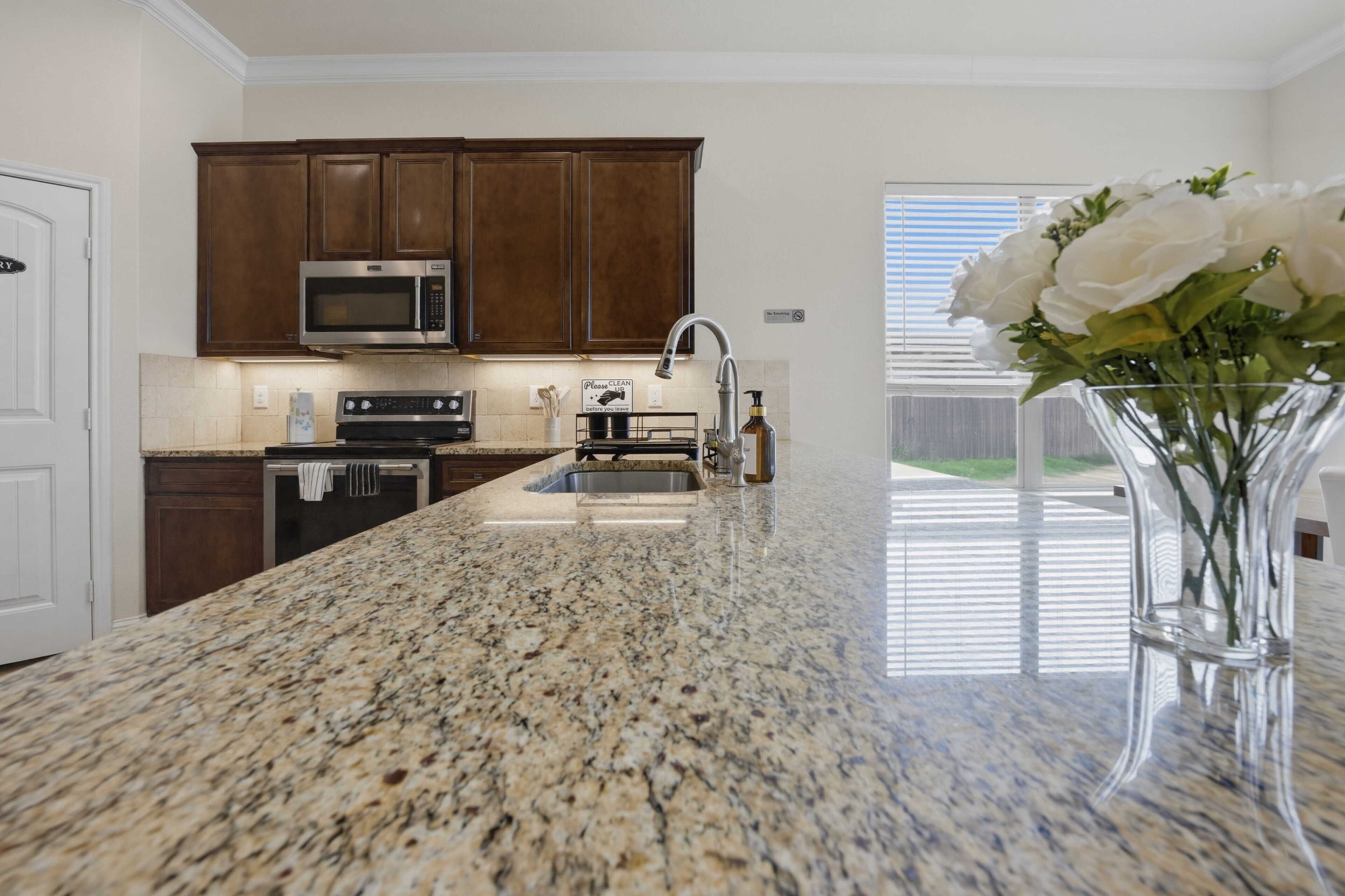 A kitchen with granite countertops, stainless steel appliances, and wooden cabinets.