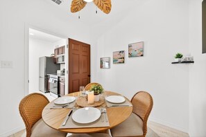 Een eetgedeelte met een ronde tafel, stoelen en een deur naar een keuken.