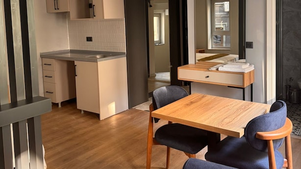A modern kitchen with a built-in island, a dining area with a wooden table and chairs, and a bathroom with a shower and a toilet. - Hotel Karakoy Corner Port (İstanbul)