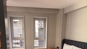A bedroom with a bed, two windows, a wooden floor, and a ceiling light. - Hotel Karakoy Corner Port (İstanbul)
