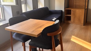 A modern room with a wooden table, black sofa, and a built-in wooden shelving unit. - Hotel Karakoy Corner Port (İstanbul)