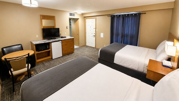 A hotel room with a bed, a desk with a television, a chair, and a wardrobe. - Ste Anne Hotel (Ste Anne)