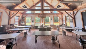 A spacious room with high ceilings, wooden beams, large windows, and tables and chairs arranged for dining. - The Landgrove (Londonderry)
