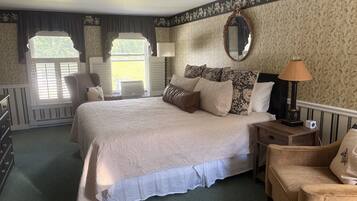 Une chambre à coucher avec un grand lit, une table de chevet avec une lampe, une chaise et une fenêtre avec des rideaux.
