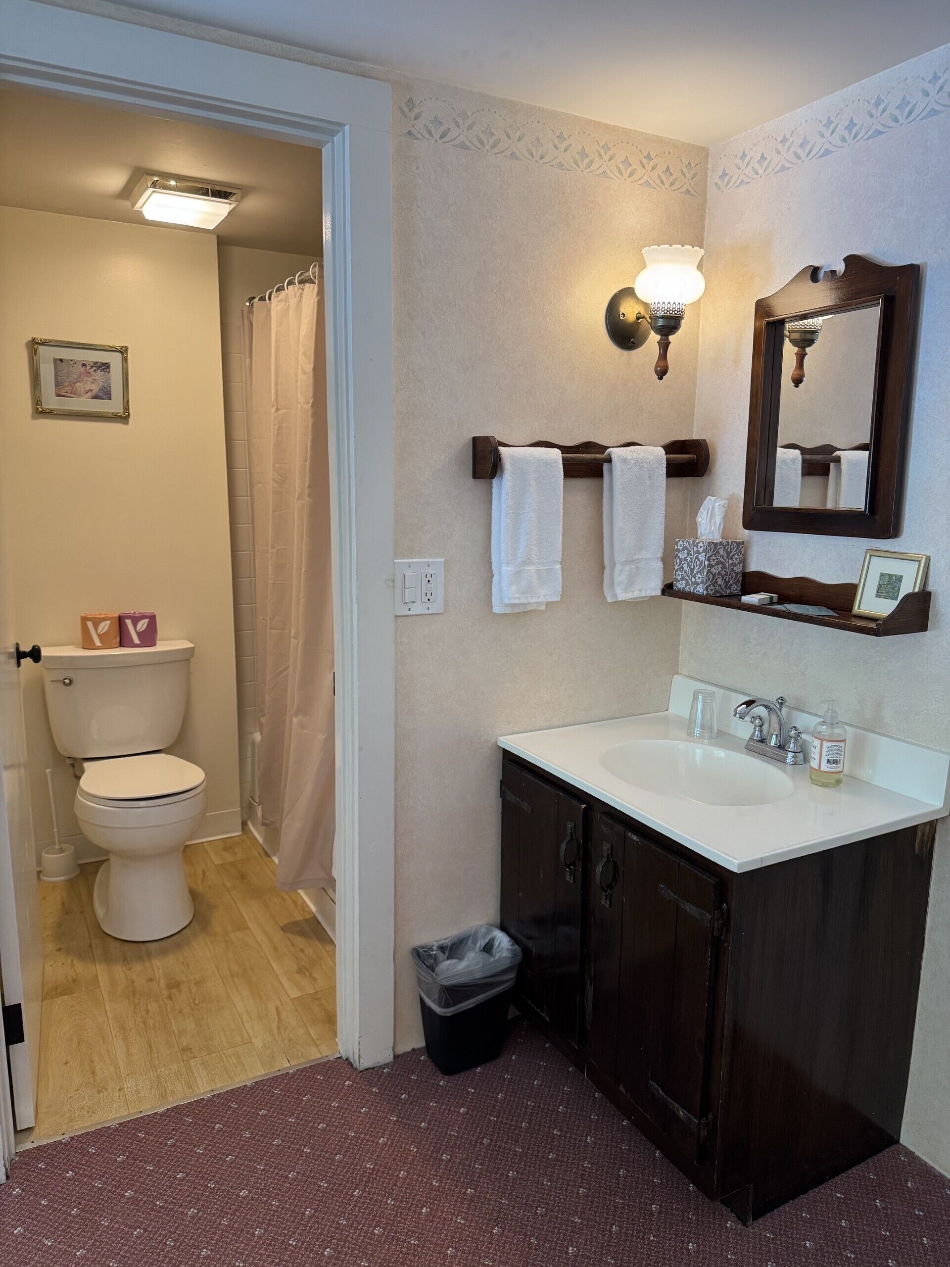 Un baño con inodoro blanco, lavamanos con espejo y cortina de ducha.
