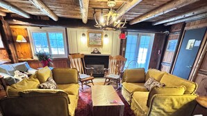 A rustic interior with wooden beams, a fireplace, and a chandelier. - The Landgrove (Londonderry)