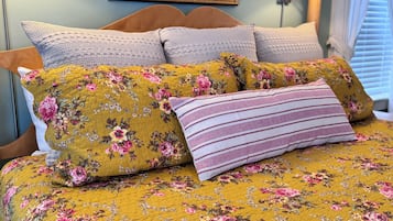 Una cama con ropa de cama floral y varias almohadas.