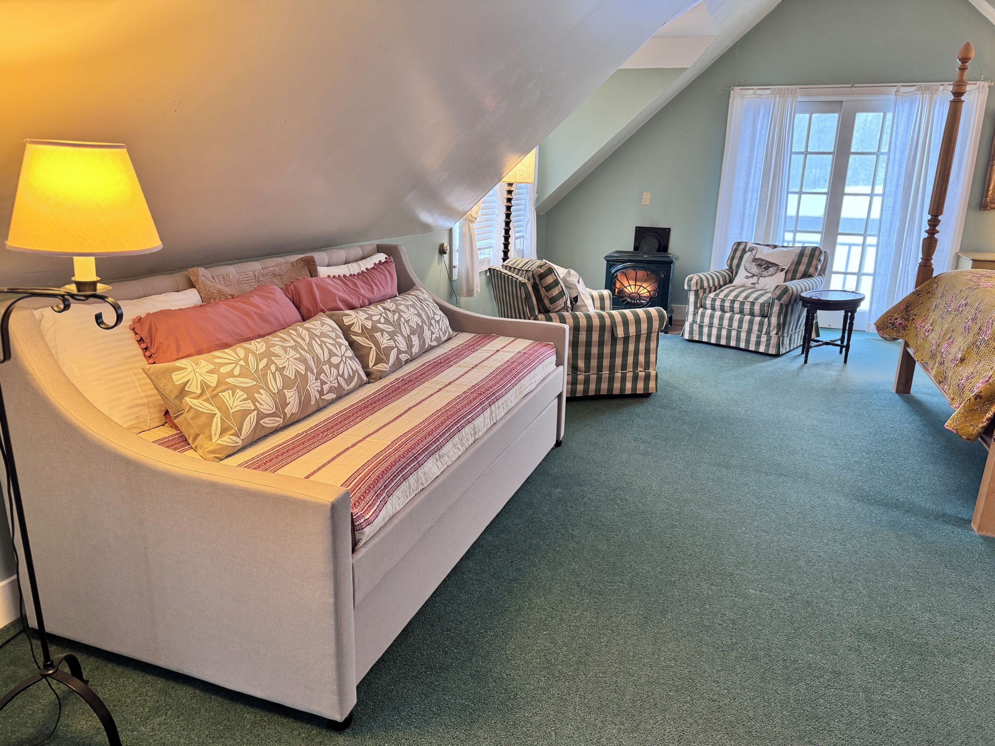 Ein gemütliches Zimmer mit einem Bett, einem Sofa, einem Sessel, einem Tisch und einem Kamin.