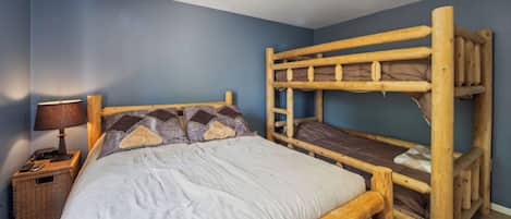 A bunk bed room with a nightstand, lamp, and a ceiling fan.
