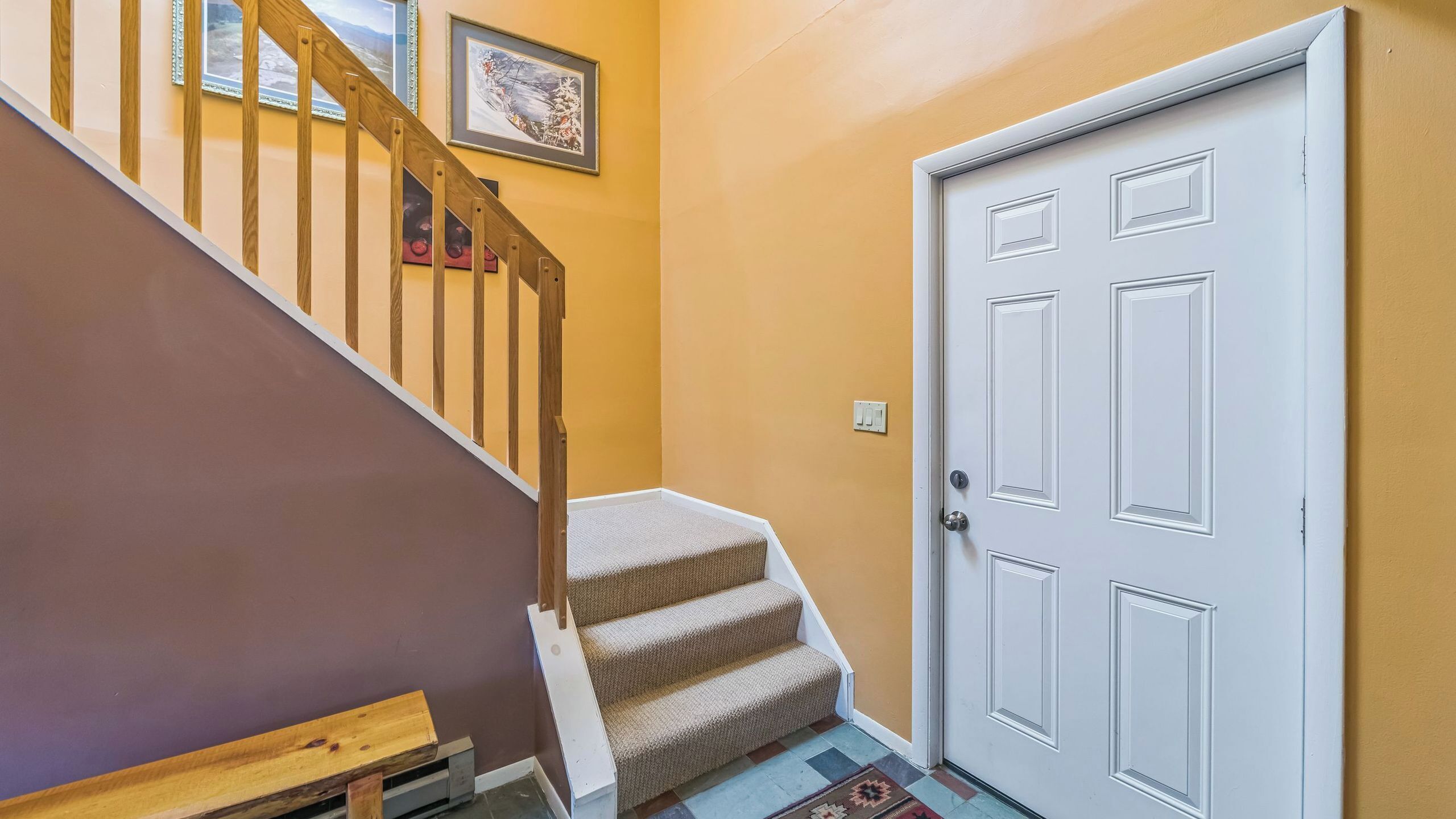 A staircase with wooden railings, a carpeted landing, and a white door with a keyhole.