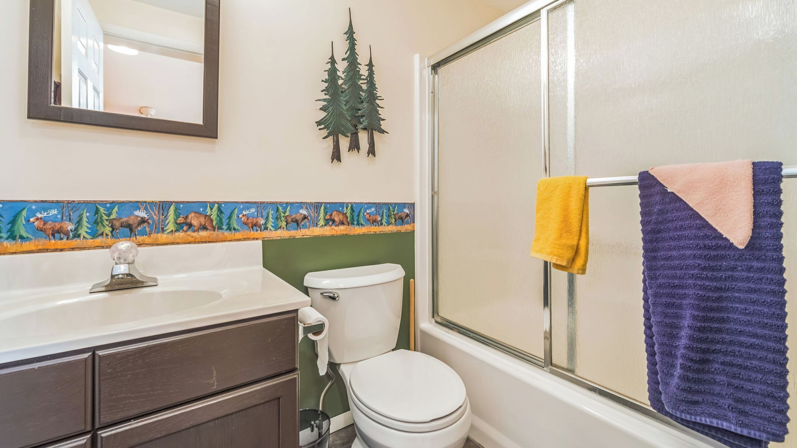 Een badkamer met toilet, wastafel en spiegel.